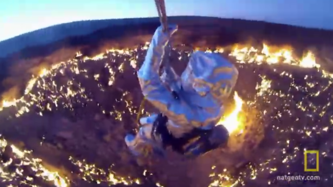 Wearing a heat-resistant aluminum suit and suspended on a wire above Darvaza gas crater, George Kourounis prepares to descend to the fiery floor of the pit.